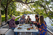 Freunde genießen Wein und Häppchen an Deck eines Le Boat Horizon 4 Hausboots, das an der Themse in Henley-on-Thames vor Anker liegt, Oxfordshire, England, Großbritannien, Europa