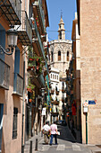 Two men walk down a narrow street in the Old Town of Valencia, Spain.