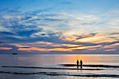 Two girls wade into the sea at sunset. Phu Quoc island, Vietnam.