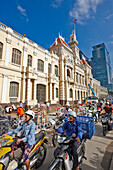 People on motorbikes drive by the People’s Committee Building in Ho Chi Minh City, Vietnam.