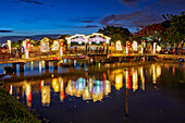  Blick auf die Cau An Hoi-Brücke, die in der Abenddämmerung beleuchtet und im Thu Bon-Fluss reflektiert wird. Antike Stadt Hoi An, Provinz Quang Nam, Vietnam. 