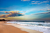 People walk along the Mui Ne Beach at sunset. Mui Ne, Binh Thuan Province, Vietnam.