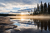 Finnland, Oulanka-Nationalpark, Blick auf See und Wald am Abend im Gegenlicht bei Sonnenuntergang