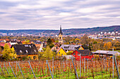  View of a picturesque village with church surrounded by autumnal vineyards under cloudy sky, Kunitz, Thuringia, Germany 