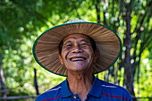  Portrait of a cheerful Cambodian man with a big smile and a sun hat, Srae Thmei, Role Bier District, Kampong Chhnang, Cambodia, Asia 