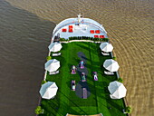  Aerial view of the river cruise ship RV Mekong Discovery (Thurgau Travel) on the Mekong River with people practicing yoga and morning exercises on the sun deck, Preaek Pou, Srey Santhor District, Kampong Cham, Cambodia, Asia 