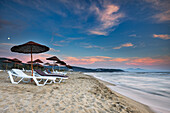 Sunbeds under parasols on the Pamucak Beach at dusk. Izmir Province, Turkey.