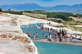 Tourists walk on the travertine terraces of Pamukkale. Denizli Province, Turkey.