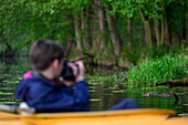  Child in kayak observes and photographs nutria, wildlife, river landscape, leisure activities, paddling, water hiking, photo tour, photo excursion, UNESCO biosphere reserve, Spreewald, Brandenburg, Germany\n 