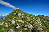  Woman sitting in front of Rifugio Mombarone hut with view of Colma di Mombarone peak with Christ statue, GTA, Grande Traversée des Alpes, Biella, Alpi Biellesi, Valais Alps, Piedmont, Italy 