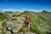  Man and woman hiking over rocky ridge on the GTA with Monte Mars in the background, GTA, Grande Traversée des Alpes, Biella, Alpi Biellesi, Valais Alps, Piedmont, Italy 