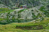  Hut Rifugio Barma stands in rocky terrain above mountain lake, Rifugio Barma, GTA, Grande Traversée des Alpes, Biella, Alpi Biellesi, Valais Alps, Piedmont, Italy 