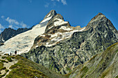  Several people standing on a meadow below Mont Dolent, Grand Col Ferret, Tour du Mont Blanc, Mont Blanc Group, Graian Alps, Aosta Valley, Italy 