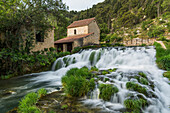 Wasserfall vor einem Haus im Krka Nationalpark, Kroatien