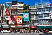 Sunlit colorful advertising billboards on buildings along the Yaowarat Road in Chinatown, Bangkok, Thailand.