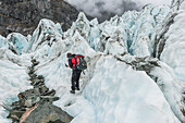 Mountaineer chopping steps into ice, Fox Glacier, Westland National Park, South Island, New Zealand
