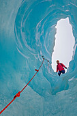  Eiskletterer blickt in eine Eishöhle, Fox-Gletscher, Südinsel, Neuseeland // MODELL veröffentlicht MR-NZ-02 