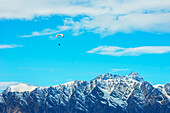  Paragliding über der schneebedeckten Remarkables-Bergkette, Queenstown, Südinsel, Neuseeland 