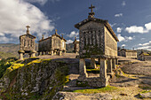  Old stone granaries, Granaries of Soajo, stand elevated against a mountain backdrop and blue sky, Viana do Castelo, Soajo, Portugal 