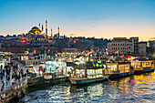 Restaurantschiffe am Ufer von Eminönü, Rüstem-Pascha-Moschee und Süleymaniye-Moschee in der Abenddämmerung, Istanbul, Türkei 