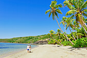 Couple walking along a sandy tropical beach, Drawaqa Island, Yasawa islands, Fiji
