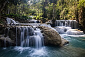 Wasser fließt über Felsen am Wasserfall Kuang Si Falls, in der Nähe von Kuang Si, Bezirk Luang Prabang, Laos, Asien