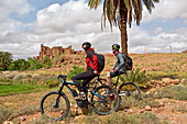 Riders on mountain bike with electric assistance in front of the Ksar of Tamedakhte, Ounila River valley, Ouarzazate Province, region of Draa-Tafilalet, Morocco, North West Africa