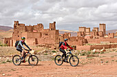 Riders on mountain bike with electric assistance in front of the Ksar of Tamedakhte, Ounila River valley, Ouarzazate Province, region of Draa-Tafilalet, Morocco, North West Africa