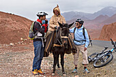 Encounter between an old man riding a mule and cyclists with mountain pedelec on the road connecting Tizi n'Tichka pass to Telouet village, Ouarzazate Province, region of Draa-Tafilalet, Morocco, North West Africa