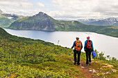 Wanderer mit Blick über den Fjord Bergsfjorden vom Berg Husfjellet, Insel Senja, Grafschaft Troms, Norwegen, Nordeuropa
