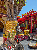 Incense altar at the seated Buddha image in the courtyard of Vihara Dharmayana, 19th century Buddhist temple. Kuta, Bali, Indonesia.