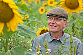  Man wearing a cap standing in a field with plants for insects and birds, Hagenbach, Rhineland-Palatinate, Germany 