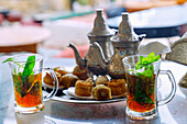 Pfefferminztee arabischer Art mit vier Stücken Hlou, tunesischer Patisserie, serviert auf Silbertablett mit Silberkannen und Serviettenhalter in tunesischem Café in Hammamet , Tunesien