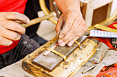  Craftsman engraving a copper bracelet with a traditional engraving tool in the souk in the Medina of Nabeul, Tunisia 