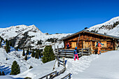  Three people on ski tour arriving at an alpine hut, Langer Grund, Kitzbühel Alps, Tyrol, Austria 