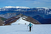 Frau auf Skitour steigt zum Monte Genzana auf, Monte Amaro im Hintergrund, Monte Genzana, Nationalpark Majella, Apenninen, Abruzzen, Italien