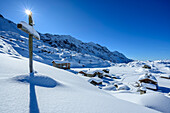 Verschneites Kreuz vor Rifugio Cristina und Alpe Prabello, Alpe Prabello, Berninagruppe, Lombardei, Italien