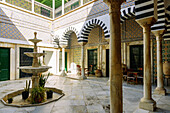  Courtyard decorated with tiles, fountains, and colorful columned arcades in the historic Dar Bach Hamba Palace in the Medina of Tunis, Tunisia 