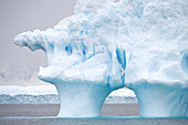 Dieser seltsam geformte Eisberg mit einem Bogen treibt vor der Cuverville-Insel auf der Antarktischen Halbinsel, Antarktis
