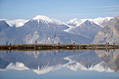 Wanderer spiegeln sich mit Bergen in stillem Bergsee in der Nähe der Sirius-Station, Insel Ella, Arktisches Grönland, Grönland, Dänemark, Nordpolarkreis, Arktis, Nordeuropa, Europa