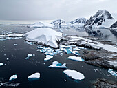  Aerial view of the impressive landscape of icebergs, rocks, and mountains on Petermann Island, Antarctic Peninsula, Antarctica 