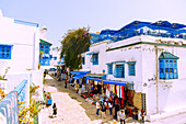  Main street Rue Habib Thameur with souvenir shops and white cube houses with Arabic balconies in the (Medina) old town of Sidi Bou Said, Tunisia 