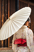 Woman wearing a traditional Japanese kimono with an umbrella in the streets of Kyoto, Japan.