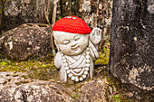 One of the cute little Buddha statues with red knitted hat and wish coins at Daisho-in Temple, Miyajima, , Hiroshima Prefecture, Japan.