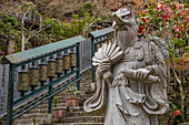 Tengu, with wings and long nose, statue next to a stairway with spinning metal wheels at the Daisho-in Temple, Miyajima Island, Hiroshima Prefecture, Japan.