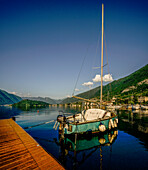  Boat at the jetty, Lenno marina, Lenno and the mountains in the background, Lenno, Lake Como, Italy 