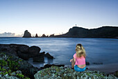 Girl sitting on rocks admiring sunrise at Pointe des Chateaux, Grande-Terre, Guadeloupe, overseas region of France,Leewards Islands, Lesser Antilles, Caribbean