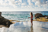 Girl waiting for wave at Blowhole beach at Pointe des Chateaux, Grande-Terre, Guadeloupe, overseas region of France,Leewards Islands, Lesser Antilles, Caribbean