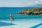 Young woman posing on the edge of the swimming pool of "La Toubana" hotel and spa, Sainte-Anne, Guadeloupe, overseas region of France,Leewards Islands, Lesser Antilles, Caribbean