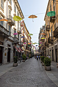 kleine Gasse in der Altstadt von Alessandria mit aufgehängten Regenschirmen, Piemont, Italien